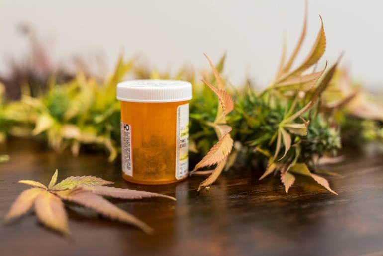 une bouteille de médicament et de feuilles de chanvre sur une table en bois