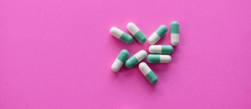 pilule de médicament blanc et bleu sur textile rose